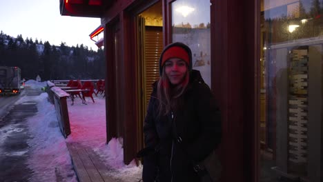 Young-blonde-girl-with-cold-expression,-warmly-dressed-at-the-door-of-her-ski-resort