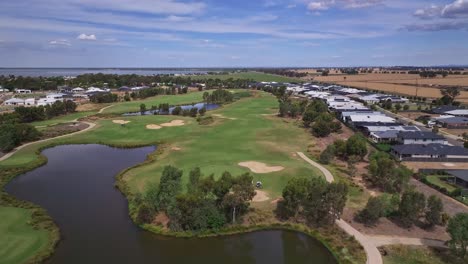 Low-aerial-view-of-a-fairway-and-billabong-on-a-golf-course-in-the-middle-of-a-new-residential-estate