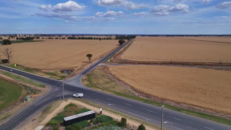 A-country-cross-road-with-wheat-fields-stretching-to-the-horizon-in-Victoria,-Australia