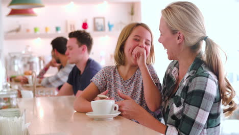 Mother-and-young-daughter-sitting-at-the-counter-in-a-cafe