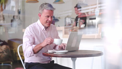 Geschäftsmann-An-Einem-Tisch-In-Einem-Café-Mit-Laptop