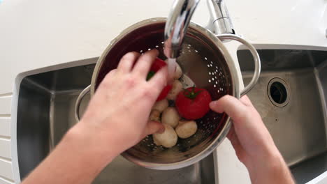 Point-of-view-of-man-washing-vegetables-in-a-colander