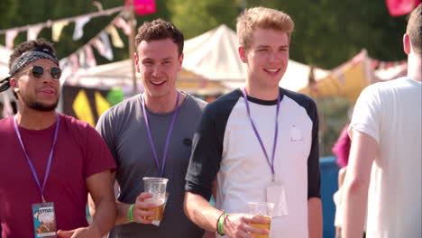 Three-male-friends-walking-at-a-music-festival,-slow-motion