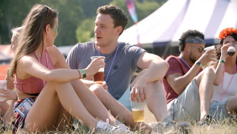 Couple-sitting-on-grass-talking-at-music-festival