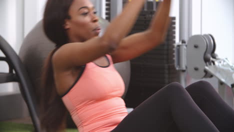 Woman-doing-medicine-ball-sit-ups-with-a-trainer-in-a-gym