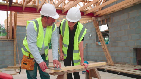 Carpenter-With-Female-Apprentice-Measuring-And-Cutting-Wood