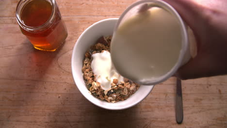 Point-Of-View-Shot-Of-Pouring-Muesli-And-Yogurt-Into-Bowl
