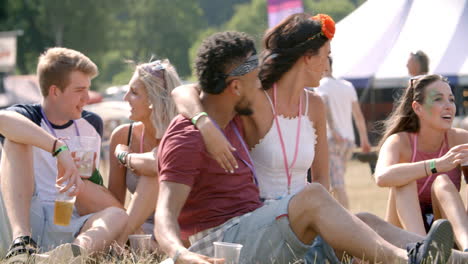 Friends-sitting-on-grass-taking-selfie-at-a-music-festival