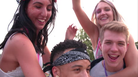Young-friends-piggy-backing-at-a-music-festival,-close-up