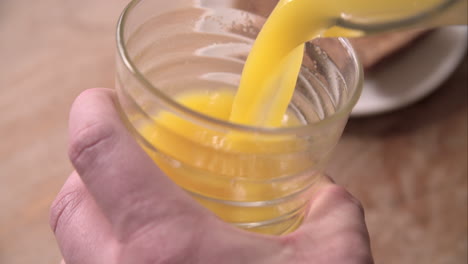 Slow-Motion-Shot-Of-Pouring-Orange-Juice-Into-Glass-From-Jug