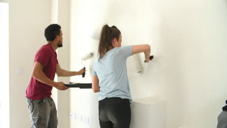 Young-couple-decorating-home-with-paint-rollers
