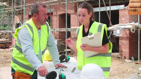 Builder-On-Site-Discussing-Work-With-Female-Apprentice