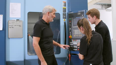 Two-Apprentices-Working-With-Engineer-On-CNC-Machinery