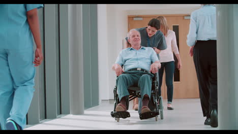Krankenschwester-Schiebt-älteren-Patienten-Im-Rollstuhl-Den-Korridor-Entlang