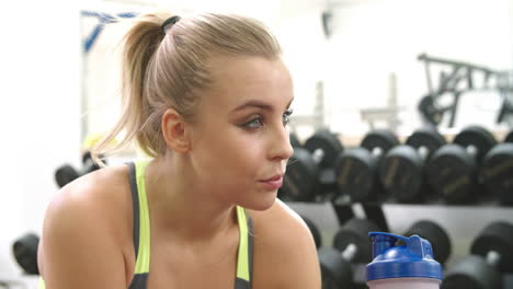 Young-caucasian-woman-drinking-a-protein-shake-at-a-gym