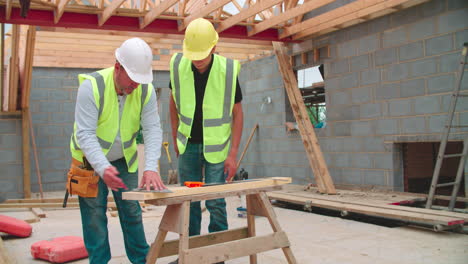 Carpenter-With-Male-Apprentice-Measuring-And-Cutting-Wood