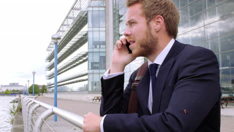 Young-businessman-talking-on-phone-while-walking