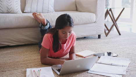 Teenager-Mädchen-Liegt-Auf-Dem-Boden-Und-Macht-Hausaufgaben-Mit-Einem-Laptop-Computer,-In-Voller-Länge,-Erhöhte-Ansicht