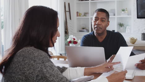Middle-aged-African-American-man-with-laptop-giving-financial-advice-to-a-woman-during-a-meeting-at-her-home