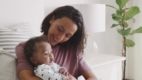 Happy-millennial-African-American-mother-sitting-up-in-bed-holding-her-baby,-close-up