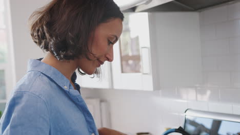 Millennial-African-American-woman-standing-in-the-kitchen-cooking-on-the-hob,-side-view,-close-up