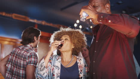 Senior-Couple-Drinking-Shots-And-Dancing-In-Bar-Together