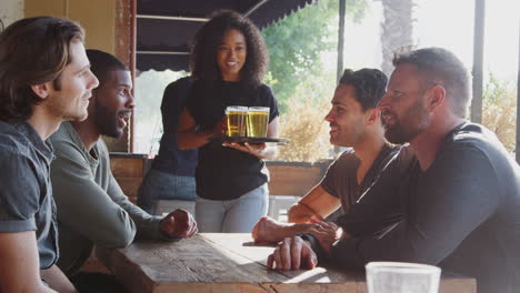 Waitress-Serving-Drinks-Outdoors-To-Group-Of-Male-Friends-Meeting-In-Sports-Bar