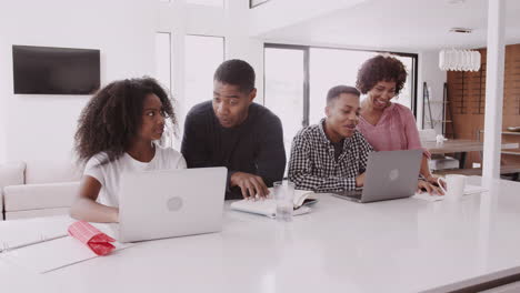 Middle-aged-black-parents-helping-their-teenage-kids,-doing-their-homework-using-laptops