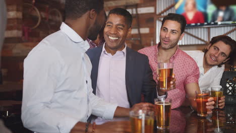 Eine-Gruppe-Männlicher-Freunde-Trinkt-Abends-Bier-An-Der-Bar-Und-Stößt-An