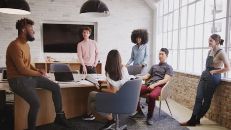 Six-millennial-creative-coworkers-in-discussion-in-an-office-meeting-room,-full-length