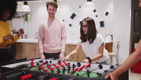 Millennial-creative-business-colleagues-take-a-break-playing-table-football-at-work,-close-up