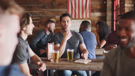 Grupo-De-Amigos-Varones-Reunidos-En-Un-Bar-Deportivo-Bebiendo-Cerveza-Y-Hablando