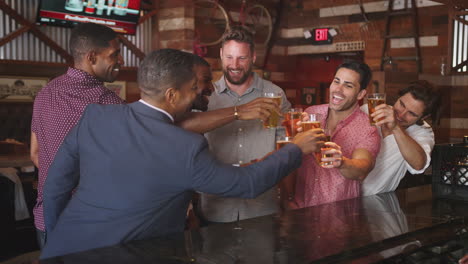 Group-Of-Male-Friends-On-Night-Out-Drinking-Beer-At-Bar-Together-Making-A-Toast