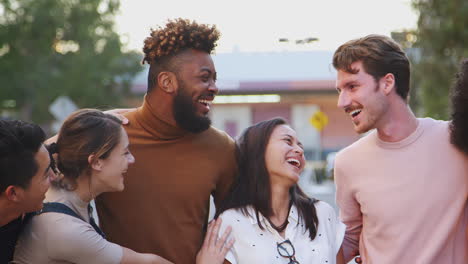 Six-millennial-hipster-friends-standing-in-a-city-street-smiling-to-camera,-panning-shot