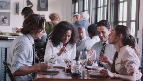 Business-Colleagues-Sitting-Around-Restaurant-Table-Enjoying-Meal-Together