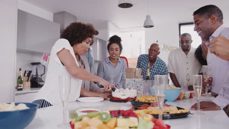 Drei-Generationen-Schwarze-Familie-Stehen-Um-Einen-Tisch,-Während-Mutter-Auf-Der-Geburtstagsfeier-Den-Kuchen-Anschneidet