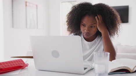 Young-teenage-black-girl-using-laptop-computer-at-home,-close-up