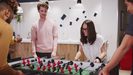Young-business-creatives-playing-table-football-together-at-work-celebrate-a-goal,-close-up