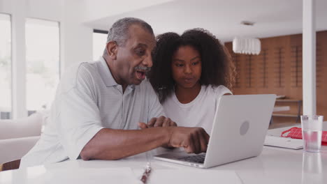 Una-Adolescente-Negra-Ayudando-A-Su-Abuelo-A-Usar-Una-Computadora-Portátil-En-Casa,-De-Cerca