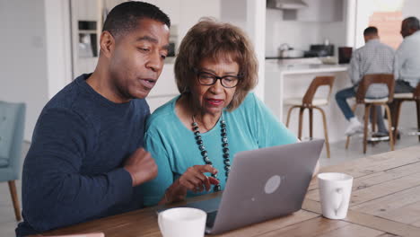 Middle-aged-black-man-helping-his-mother-use-a-laptop-computer-at-home,-close-up