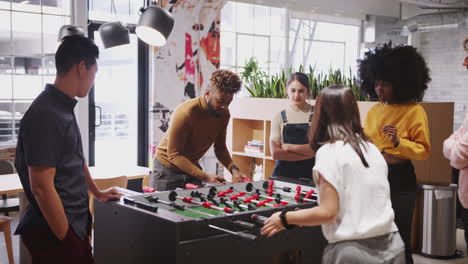 Young-business-creatives-take-a-break-playing-table-football-at-work