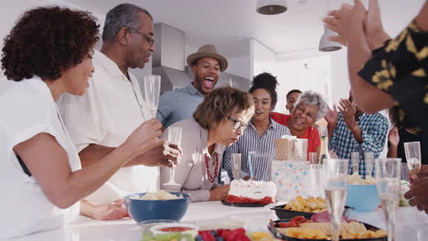 Senior-Schwarze-Frau-Bläst-Die-Kerze-Auf-Geburtstagstorte-Während-Einer-Feier-Mit-Ihrer-Familie-Aus