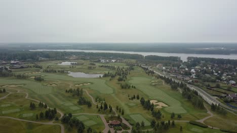Aerial-shot-of-golf-fields-and-township-near-the-river