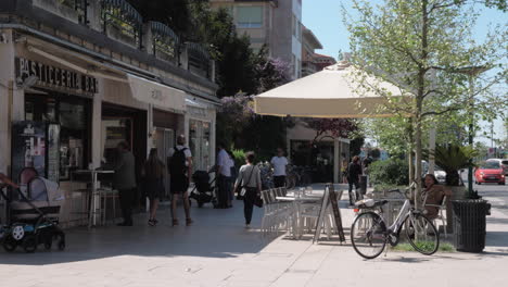 Calle-Con-Gente-Caminando-Y-Cafetería-Al-Aire-Libre-En-La-Isla-Lido,-Italia.