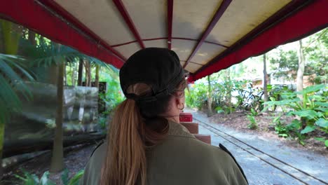 Women-sightseeing-riding-on-scenic-train-traveling-through-an-enchanting-lush-tropical-location