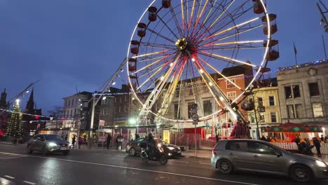 Wet-street-reflecting-lights-from-Ferris-wheel-in-centre-of-Cork,-Ireland