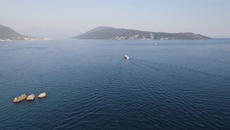 Tourist-boat-sails-in-the-Bay-of-Kotor,-Herceg-Novi,-hilly-seaside-landscape-in-Adriatic-sea