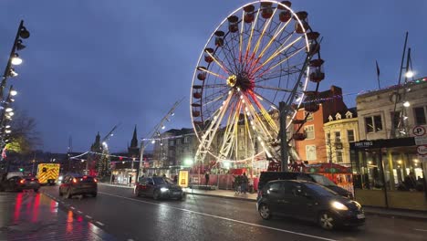 Street-traffic,-night-sky-and-lights-on-a-Ferris-wheel-Christmas-time-Cork,-Ireland