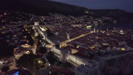 Dubrovnik-city-at-night-illuminated-by-street-lights,-cars,-and-spotlights-on-historic-walls