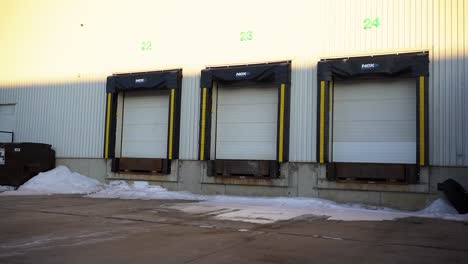 4K-Gimbal-Daytime-Morning-Establishing-Shot-Back-Lot-Warehouse-Distribution-Center-Loading-Bay-Doors-with-Bison-Semi-Tricks-Long-Haul-Delivery-Transportation-Supply-Chain-Vehicles